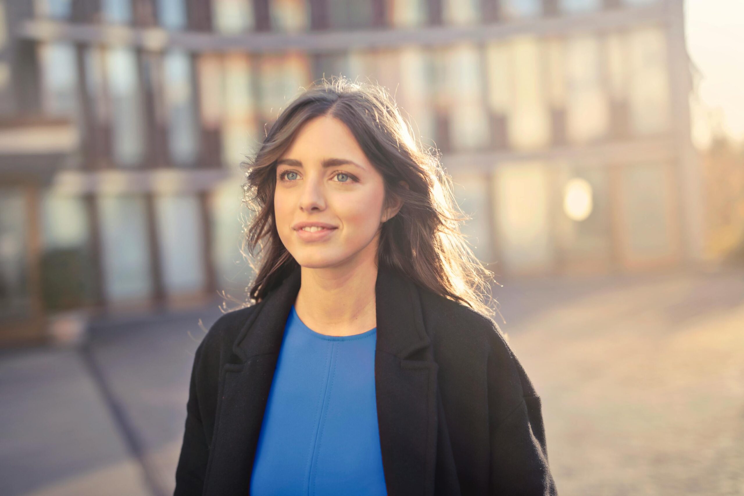 Portrait of a confident woman walking outdoors in an urban setting with a smile.